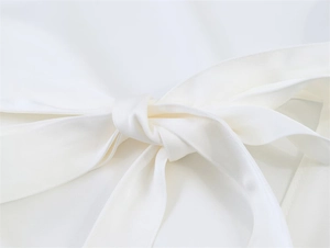 Makroaufnahme eines eleganten weißen Satinoberteils mit einem Taillenband Detail