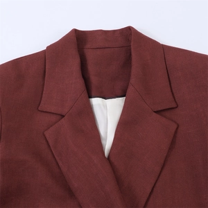 Detail van bordeauxrode revers met twill textuur en witte voering van de colbertjas