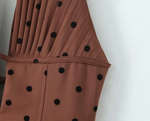 Detail van de geplooide textuur op een bruine polka dot halterjurk met stiksel
