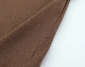 Close-up of brown knitted fabric showing fine texture and professional stitching detail