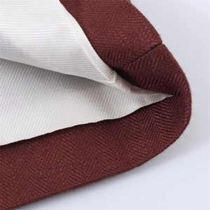 Detail van bordeauxrode twill stof met crème voering en hoogwaardige stiksels