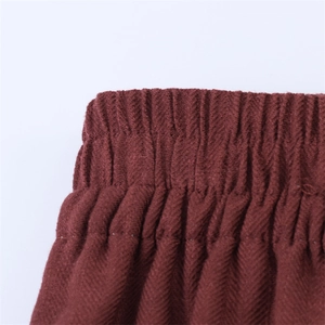 Detail van elastische tailleband op donkerrode broek met een duurzame twill-stofstructuur
