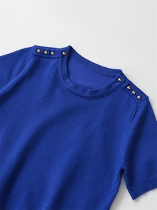 Detail of royal blue short sleeve knit top featuring gold decorative buttons on shoulders