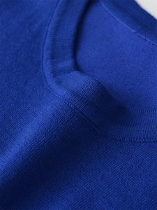 Macro detail of royal blue knit fabric showing ribbed neckline and fine texture