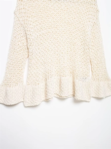 Dettaglio del top in maglia all'uncinetto bianco crema con trama traforata e maniche a campana