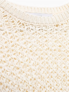 Dettaglio della trama in maglia traforata e dello scollo a costine del maglione crema
