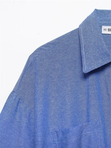 Close-up of blue cotton shirt collar with neat stitching and woven neck label detail