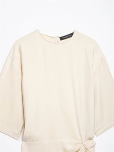Close-up of beige pleated midi dress featuring waist twist detail and lightweight fabric