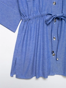Detail of blue cotton shirt featuring metal buttons, drawstring waist and side slit