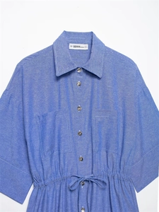 Detail of blue long-sleeve shirt with drawstring waist, double chest pockets and classic collar