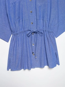 Detail of blue casual button-up shirt featuring drawstring waist and metallic buttons