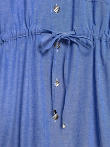 Detail view of the blue fabric texture with silver embossed buttons and waist drawstring