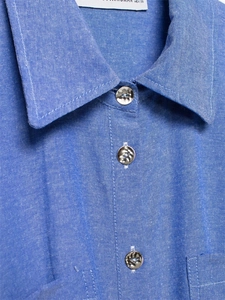 Detail of blue textured cotton shirt showing metal buttons and pointed collar