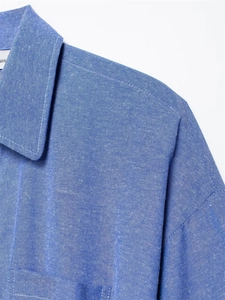 Macro detail of the standard collar and stitching on a blue linen-textured shirt