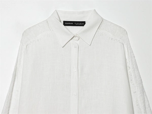Dettaglio del colletto della camicia bianca in lino con pizzo e bordi a frange