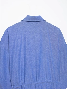 Close-up detail of blue cotton denim shirt featuring a turn-down collar and elastic hemline