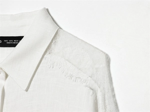 Dettagli di una camicia bianca con cuciture in pizzo sulle spalle e piccole frange