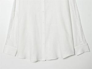 Dettaglio ravvicinato di camicia in lino bianco con bordo in pizzo sulle maniche lunghe