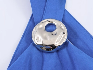 Macro detail van een gehamerde zilveren metalen ring op een levendige blauwe jurk