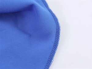 Macrodetail van hoogwaardige overlockstiksels op de blauwe gelaagde modejurk stof