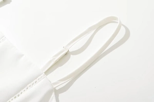 Detalle del tirante fino ajustable y encaje bordado en el vestido blanco corto