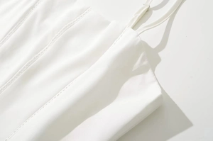 Detalle de vestido blanco con tirantes finos ajustables y bordado de encaje hueco