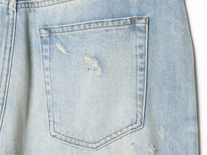 Close-up of distressed denim pocket with vintage wash and frayed edge details