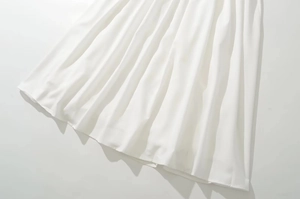 Primer plano detallado de la tela blanca del vestido con textura plisada y caída fluida