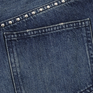 Dettaglio macro di tasca in denim blu scuro con rivetti in metallo e cuciture