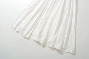 Detalle de falda larga plisada blanca que muestra pliegues finos y tejido fluido