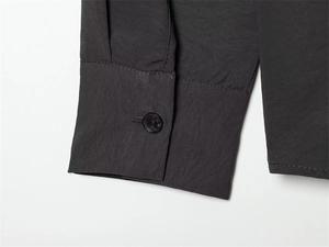 Detail of dark grey shirt cuff with a matte finish button and refined stitching