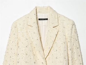 Detailaufnahme des beigen Pailletten-Tweed-Blazers mit Revers und Markenetikett
