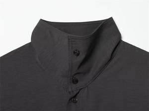 Close-up of a charcoal grey stand-up collar with three matching buttons on a draped shirt