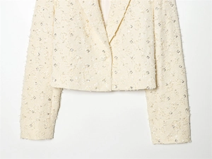 Detailaufnahme des cremefarbenen Tweed-Blazers mit Pailletten und Webstruktur