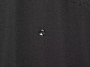 Detail of a black shirt showing double stitching and a textured two-hole button