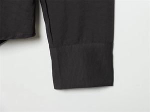 Detailed macro view of the crisp black shirt cuff showing stitching and fine fabric texture