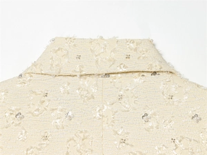 Detail von cremefarbenem Jackenkragen mit 3D-Floral-Jacquard und Perlenapplikationen