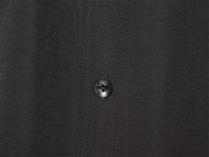 Detailed macro view of high-quality stitching and textured grey button on a black shirt