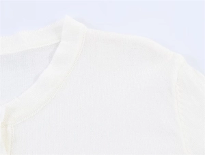 Nahaufnahme der feinen Strickstruktur und Nahtdetails am weißen Strickoberteil