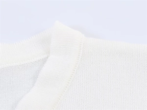 Nahaufnahme der feinen Strickstruktur und der sauberen Ausschnittnaht am weißen Pullover