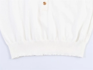 Detail eines warmweißen Strick-Cardigans mit bernsteinfarbenen Knöpfen und Rippbündchen