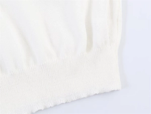 Nahaufnahme der weißen Stricktextur und des gerippten Saumdetails an einem Pullover