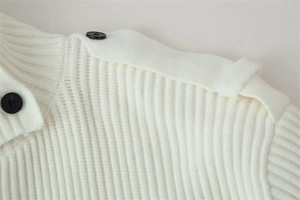 Close-up of white ribbed knit cardigan featuring shoulder tabs and black contrast buttons