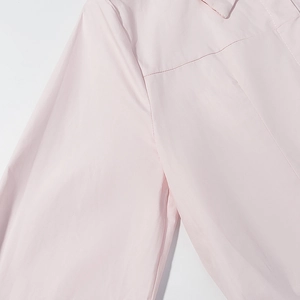 Vue détaillée des coutures de l'épaule et du dos sur ce chemisier rose pâle à manches longues