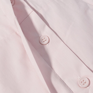 Détail de trois boutons roses circulaires sur la patte de boutonnage en coton doux