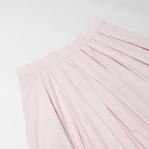 Détail d'une jupe plissée rose clair avec couture précise à la taille et tissu en coton