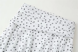 Close-up of white mesh fabric with black polka dots featuring layered pleats and inner lining