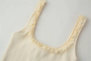 Detail of cream ribbed tank top showing the delicate lace trim around the U-shaped neckline