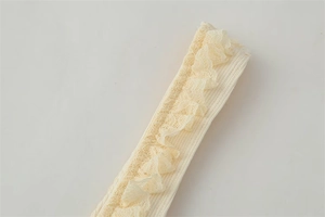 Detailed view of cream ribbed knit fabric with delicate layered lace trim edges