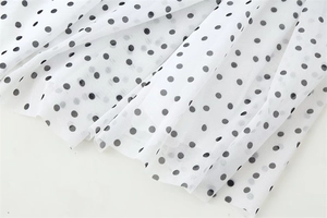 Close-up of lightweight white mesh fabric with black polka dots for women skirts